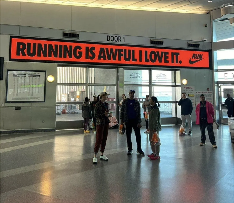 Photo of runners underneath a Nike sign saying "running is awful i love it"