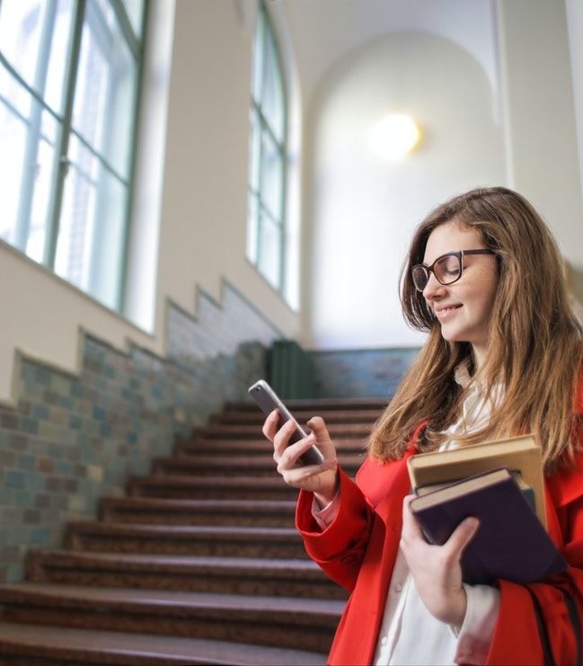 Business casual woman holding books and texting smart replies